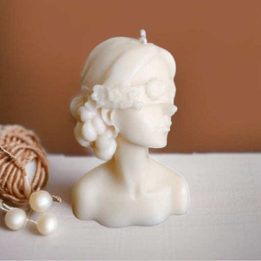 Blindfolded lady candle placed on a mat with pearls around