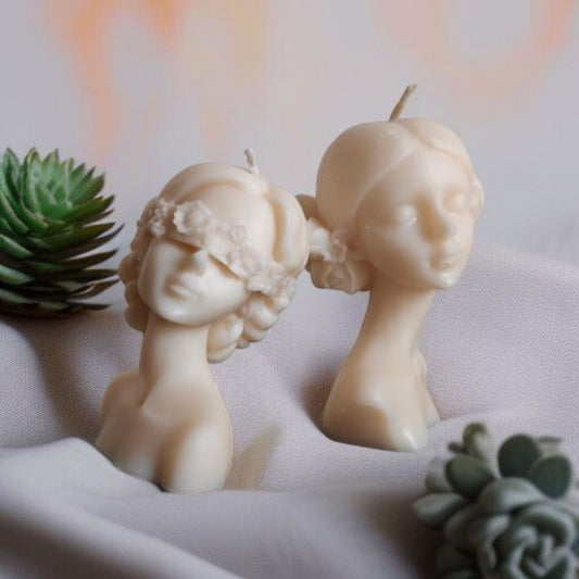 2 lady candles with floral hair bun on a cloth