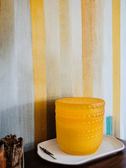 Yellow dotted jar candle on a white plate