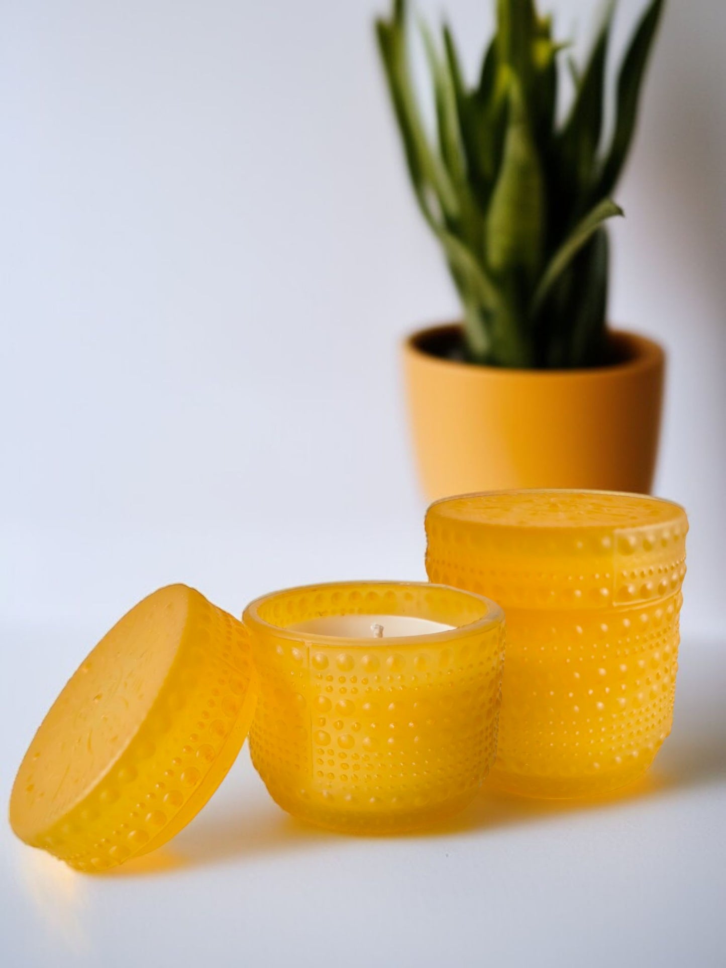 Yellow dotted jar candle placed beside a plant
