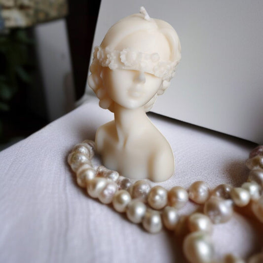 Blindfolded lady candle placed on a mat with pearls around