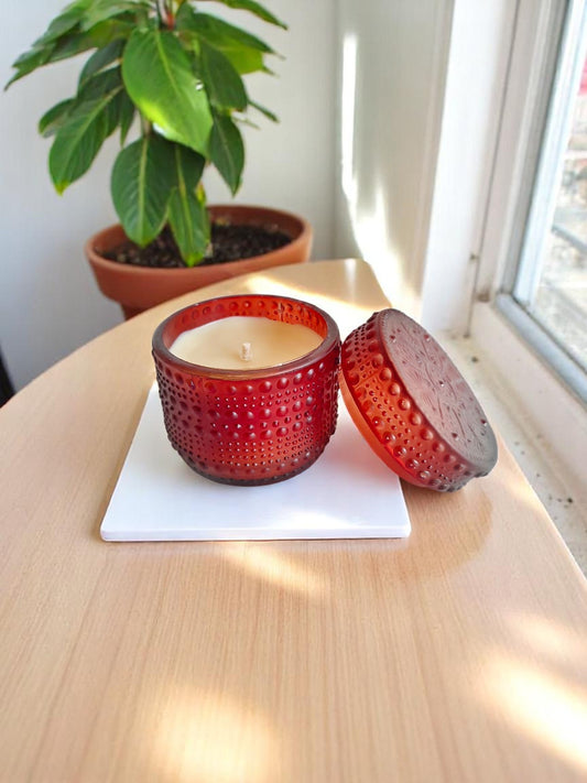 Brown dotted jar candle on a white square coaster