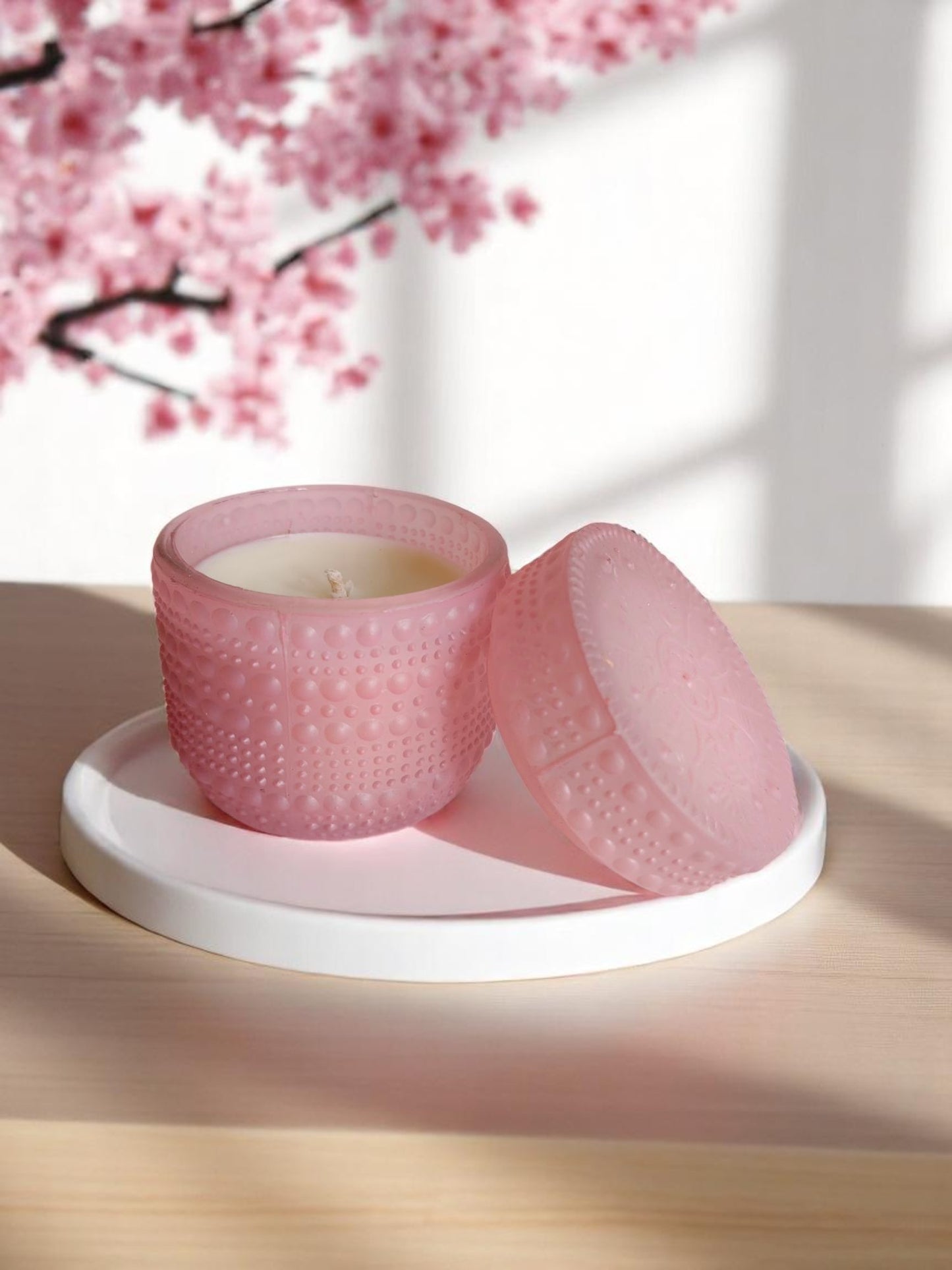 Pink dotted jar candle on a white plate