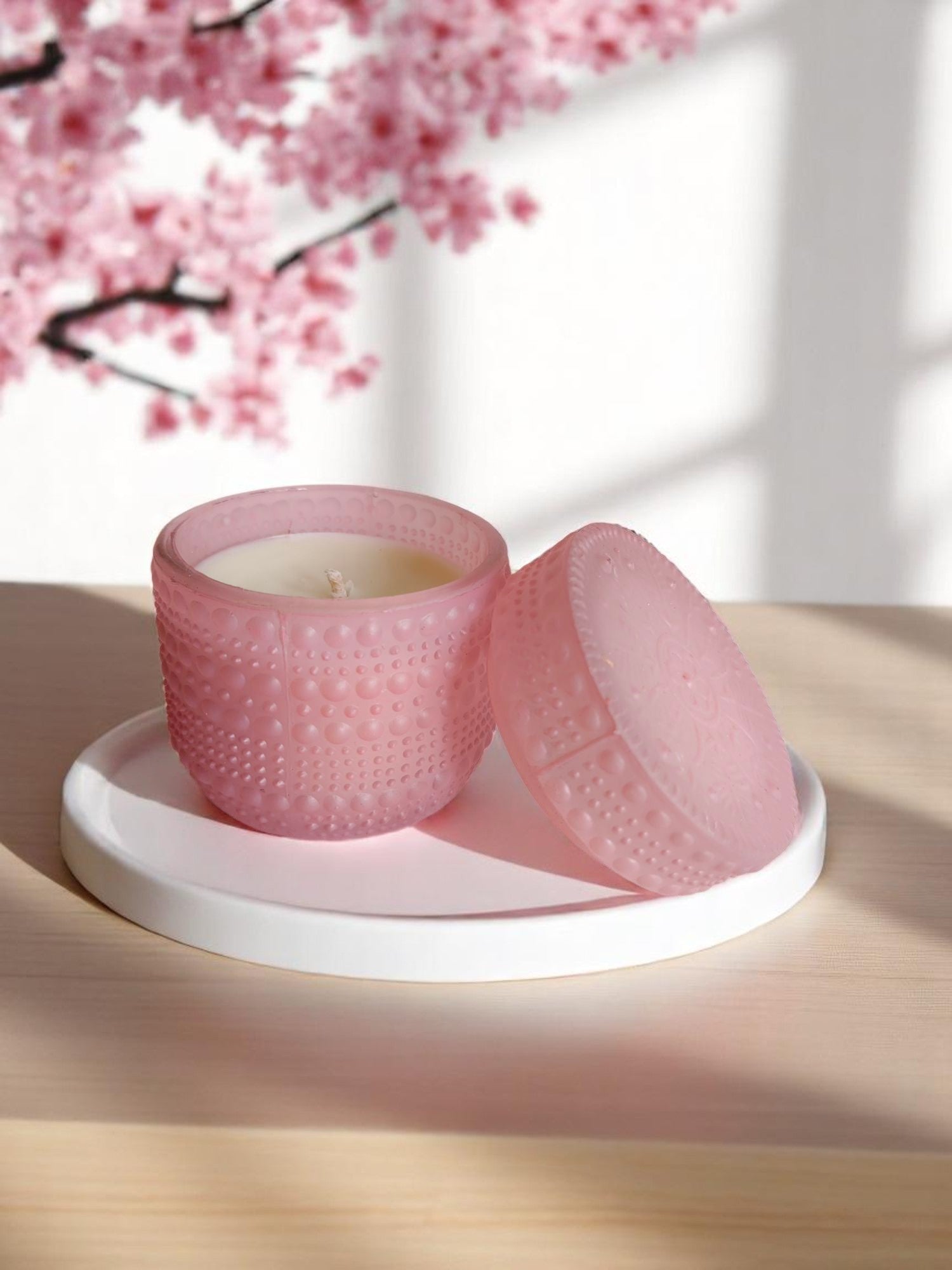 Pink dotted jar candle on a white plate