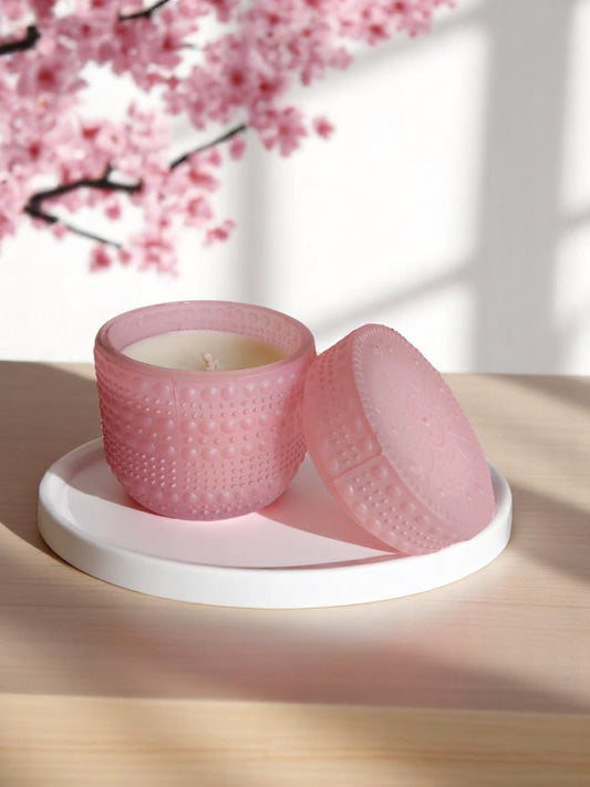 Pink dotted jar candle on a white plate