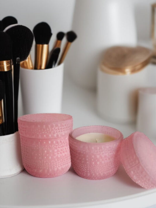Pink dotted jar candle placed beside makeup brushes