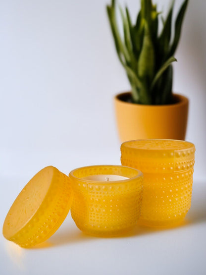 Yellow dotted jar candle placed beside a plant