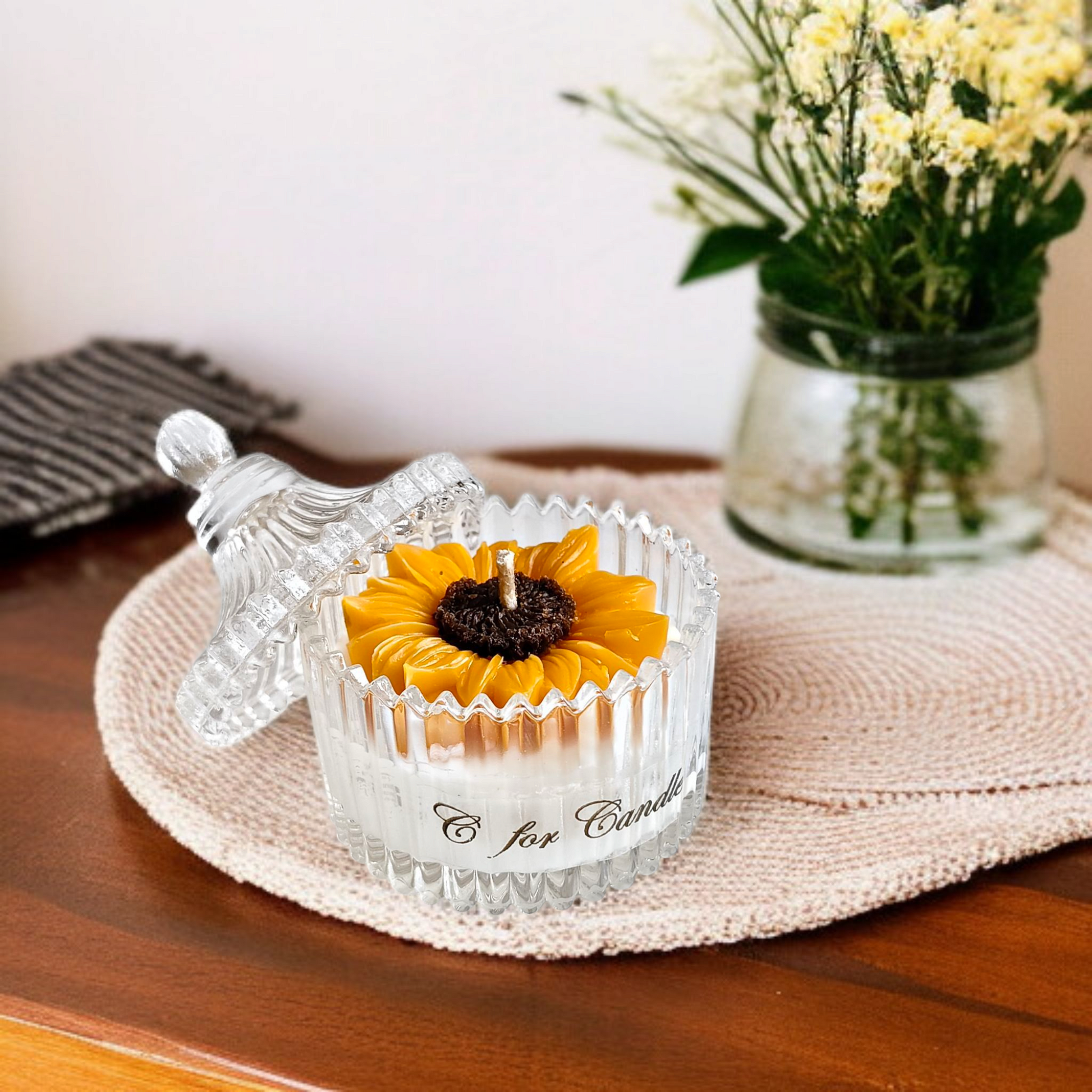 Sunflower candle in a crystal glass jar on a mat
